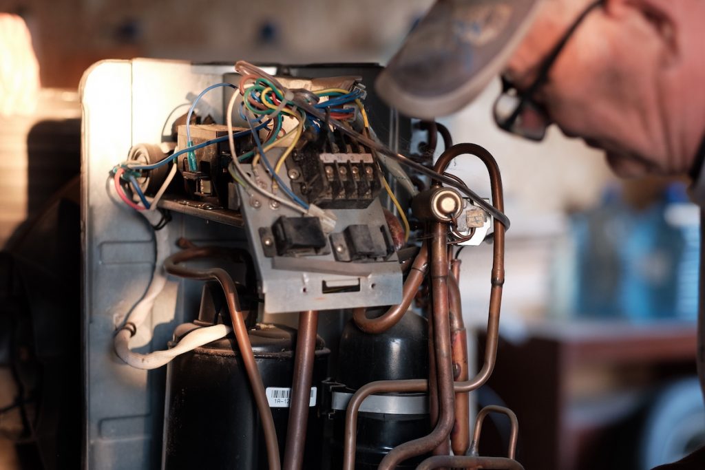 Here's Why Your Air Conditioner Isn't Working 4 A person leaning over an air conditioning interior system.
