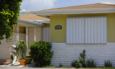Main Home 19 Outside of a yellow home with shuttered windows.