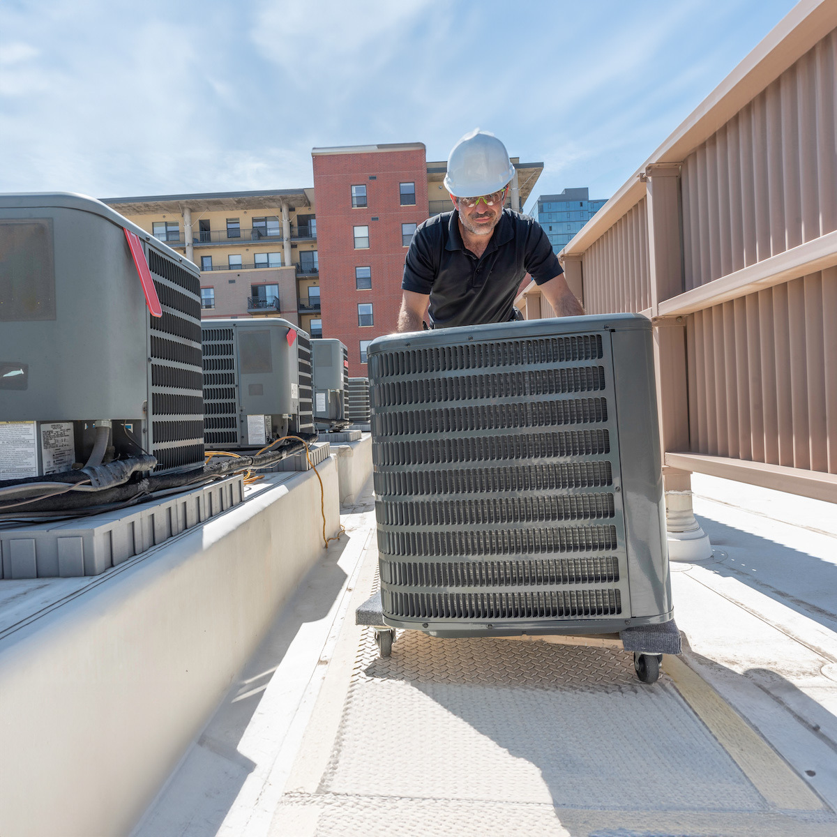 A contractor moving an AC unit on wheels.