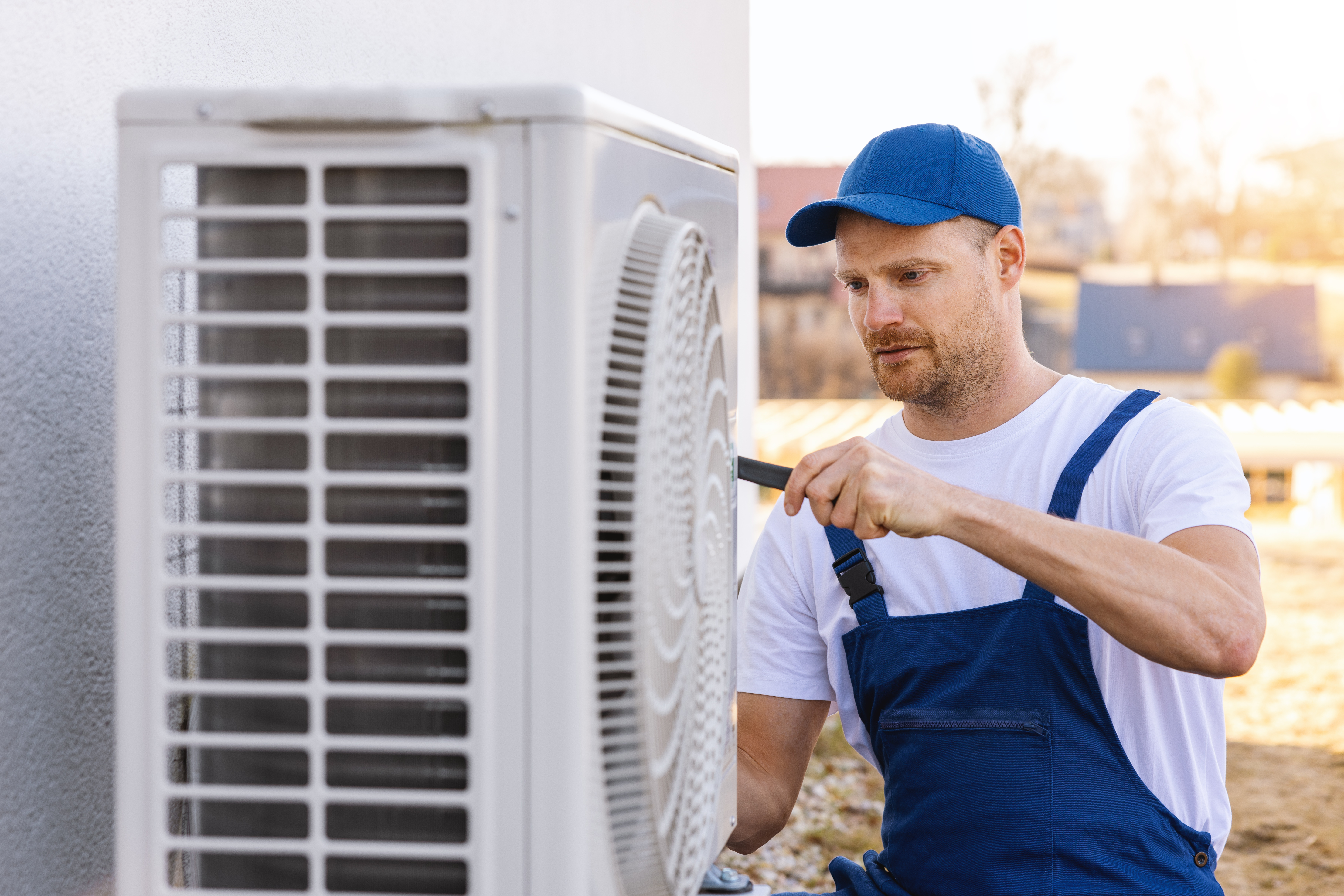 HVAC technician inspecting an outdoor air conditioning unit at a home.